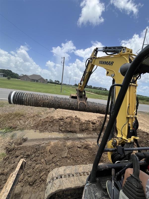 Excavator handling a drainage pipe on a Gator job site
